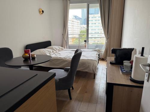 a room with a bed and a table and a window at Appartement cosy à Paris en métro -balcon & wifi in Puteaux