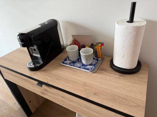 a table with a coffee maker and cups on it at Appartement cosy à Paris en métro -balcon & wifi in Puteaux