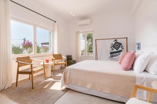a bedroom with a bed and a table and chairs at Simple House Mykonos Sunset in Mikonos
