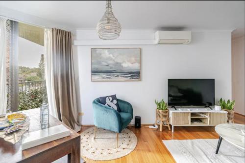 a living room with a blue chair and a television at Ultimate Beach Pad in Sydney