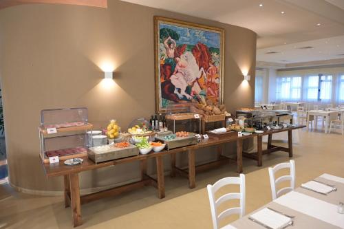 a room with two tables with food and a painting on the wall at Grand Hotel la Chiusa di Chietri in Alberobello