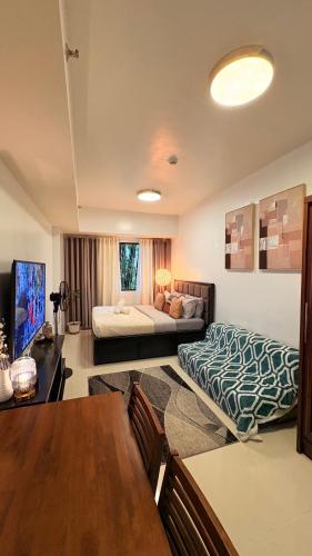 a living room with a bed and a table at Suite Escapes at Brenthill Baguio in Baguio