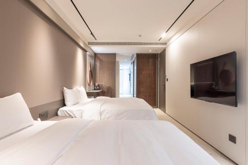 two beds in a hotel room with a flat screen tv at Green Hotel in Magong