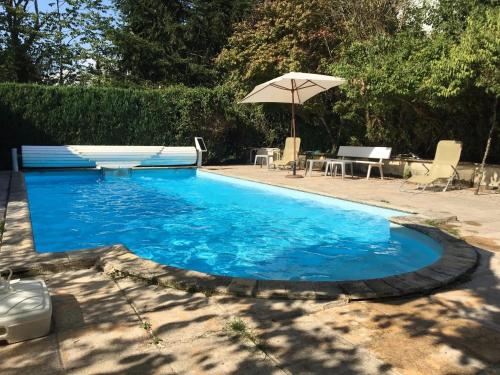 a pool with an umbrella and a table and chairs at Villa 3 chambres à Saint-Cirgues-de-Malbert avec piscine in Saint-Cirgues-de-Malbert