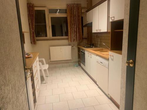 a kitchen with white cabinets and a white tile floor at Appartement 2 chambres à Place Coronmeuse in Herstal