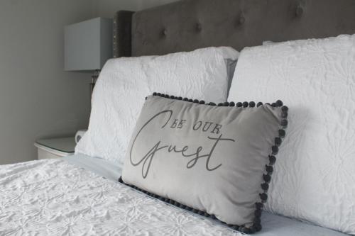 a pillow that says be our guest sitting on a bed at The Fairways, CastleBlayney in Castleblayney
