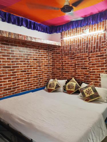 a bed in a room with a brick wall at Mirvana Guest House & Camel safari in Jaisalmer