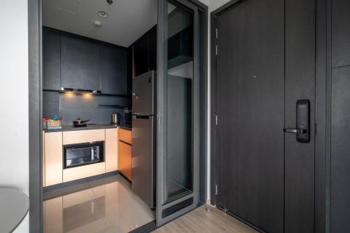 a small kitchen with black cabinets and a refrigerator at Vacaystation Edge Central Pattaya in Pattaya Central