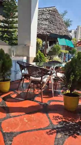 a patio with a table and chairs and a building at Villa Buerk Serena Suite Bed & Breakfast, Wi-Fi, Pool in Mombasa