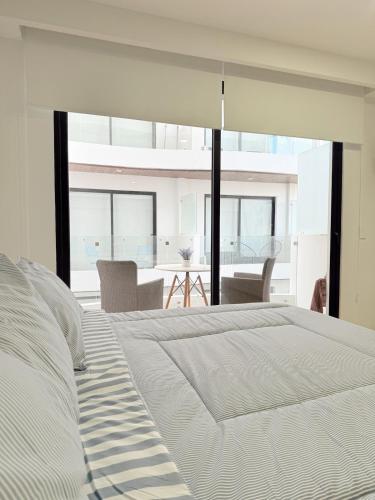 a bedroom with a large white bed and a dining room at NEW Luxury Modern Condo by Menesse in Playa del Carmen