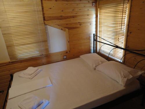 a bed in a room with wooden walls and windows at Zeus-Village οικισμός φινλανδικών chalet με πισίνες & γυμναστήριο in Mólos