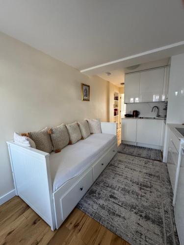 a white couch in a living room with a kitchen at Sela House - Luton Airport in Luton