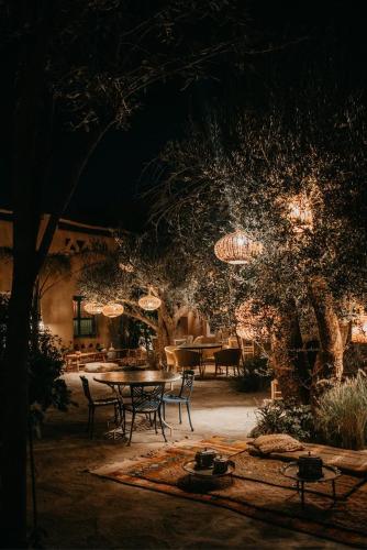 a patio with a table and chairs at night at Agafay Desert Hotel in El Karia