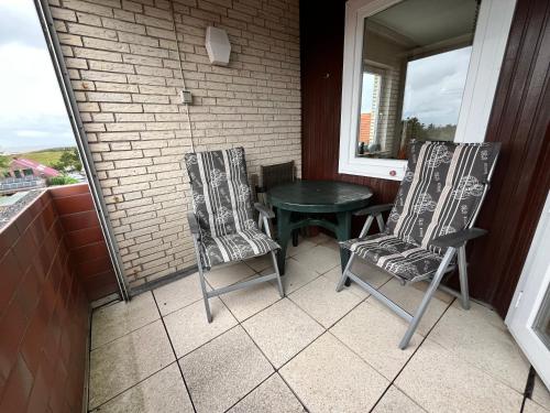 a porch with two chairs and a table and a window at Apartment CAPTAIN'S LODGE in Norddeich