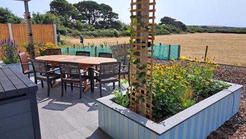 a patio with a table and chairs and flowers at Longshore Drift in Weymouth