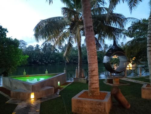 a resort with a pool and a palm tree at Luvi Lucas River Side in Weligama