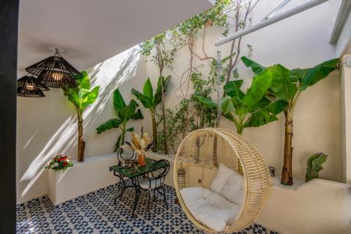 a room with plants and a wicker chair and a table at Dar Bonita in Marrakech