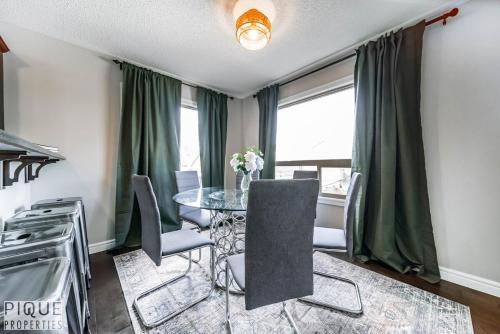 a dining room with a glass table and chairs at 5BD Jungle Oasis - HotTub - BBQ - King Bed - Games - Garage in Edmonton