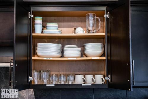 a cabinet filled with plates and cups and dishes at 5BD Jungle Oasis - HotTub - BBQ - King Bed - Games - Garage in Edmonton