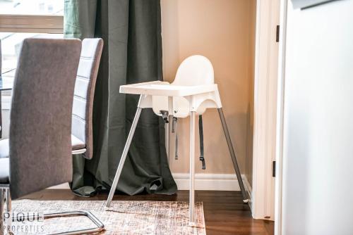 a white high stool in a room with a curtain at 5BD Jungle Oasis - HotTub - BBQ - King Bed - Games - Garage in Edmonton