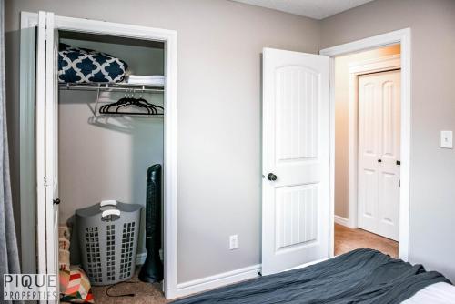 a bedroom with a closet with a bed and a door at 5BD Jungle Oasis - HotTub - BBQ - King Bed - Games - Garage in Edmonton