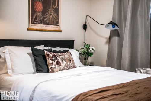 a bedroom with a bed with white sheets and a lamp at 5BD Jungle Oasis - HotTub - BBQ - King Bed - Games - Garage in Edmonton