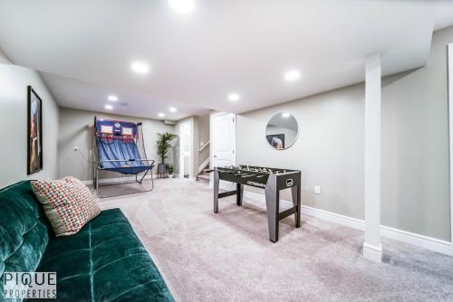 a living room with a green couch and a table at 5BD Jungle Oasis - HotTub - BBQ - King Bed - Games - Garage in Edmonton