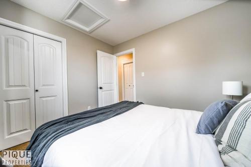 a bedroom with a white bed in a room at 5BD Jungle Oasis - HotTub - BBQ - King Bed - Games - Garage in Edmonton