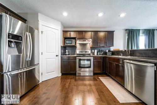 a kitchen with stainless steel appliances and wooden cabinets at 5BD Jungle Oasis - HotTub - BBQ - King Bed - Games - Garage in Edmonton