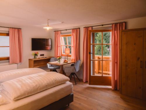 a bedroom with a bed and a desk with a table at Landgasthof Hotel Linde in Stumm