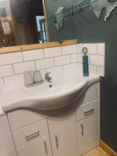 a bathroom with a white sink and a mirror at Mo-Dhachaidh B&B in Poolewe