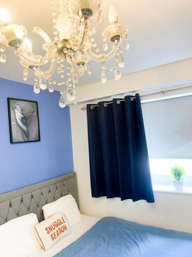 a bedroom with a chandelier and blue walls at Cozy Room in Wolverhampton City in Wolverhampton