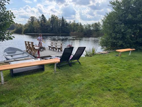 a woman standing on a dock near a lake with a boat at Lake cottage with private pier in Bälinge