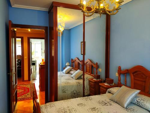 a bedroom with two beds with blue walls and a chandelier at Precioso apartamento en el Paraíso Natural 