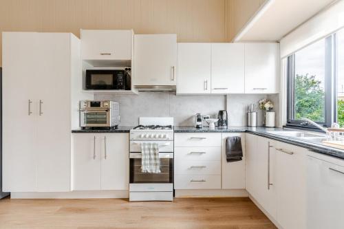 a white kitchen with white cabinets and a stove at A5Q Abnb-Style 3BR House with Balcony & 2 Free Parking Nr Portside Wharf in Brisbane