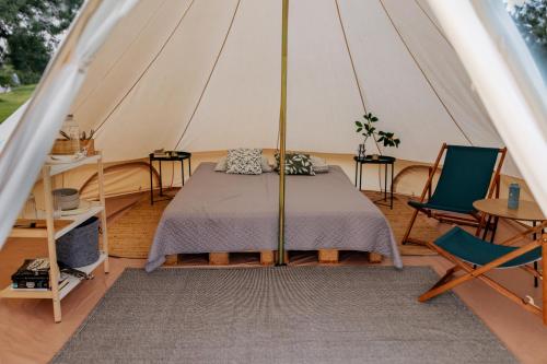 a bed in a tent with two chairs and a table at Lakeside camping in Balninkai