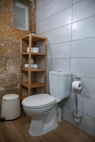 a bathroom with a white toilet and a wooden shelf at Casa San Carlo in Valletta