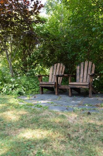 two wooden benches sitting in a park near trees at Dominion Hill Country Inn in Bocabec