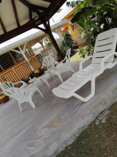a group of white chairs sitting on a porch at Villa le flamboyant in Le Marin