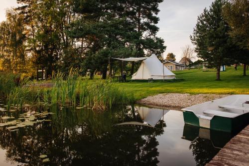 a tent next to a lake with a boat in it at Lakeside camping in Balninkai