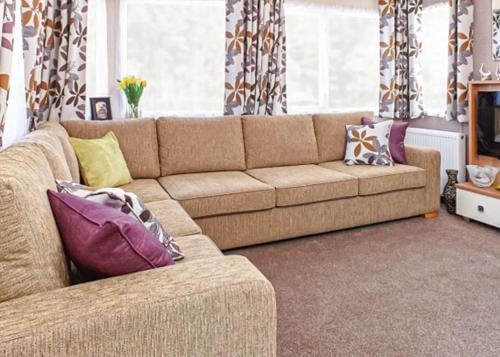 a living room with a brown couch with pillows at Stanwix Park in Silloth