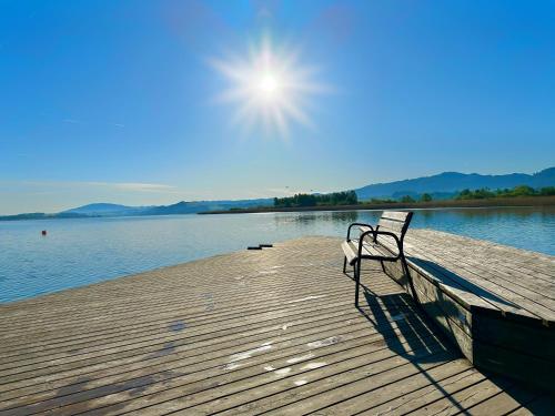 a bench sitting on a dock near the water at "FIVE" Premium Apartments Seekirchen - exklusive 4-Zi-Penthouse-Wohnung in Seekirchen am Wallersee