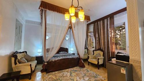 a bedroom with a canopy bed and a living room at Villa Buerk Serena Suite Bed & Breakfast, Wi-Fi, Pool in Mombasa