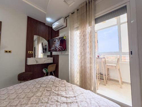 a bedroom with a bed and a window and a table at Appart de charme au centre d'Oujda in Oujda