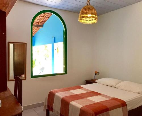 a bedroom with a bed and a large window at Pousada Igrejinha dos Carneiros in Tamandaré