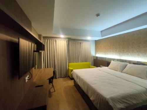 a bedroom with a large bed and a green chair at Properti Sun Premira Condotel Apartment Adi Sucipto Yogyakarta in Demangan