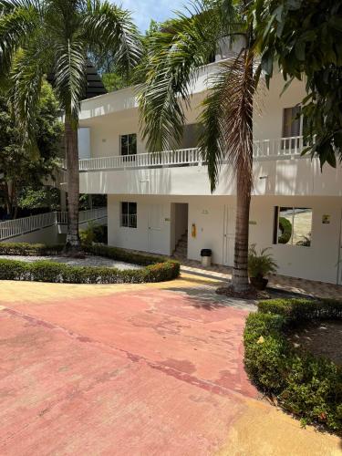 a large white building with palm trees in front of it at Eco hotel el bosque in Doradal