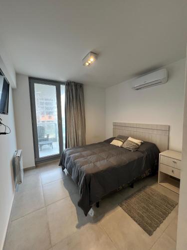 Un dormitorio con una cama y una ventana grande. en Torres al mar, en Monte Hermoso