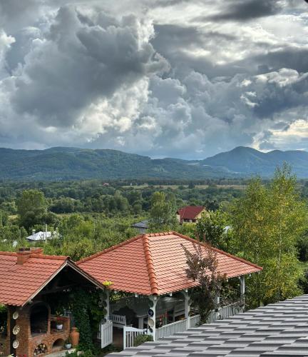 a house with a red roof with mountains in the background at Conacul Paloși in Horezu