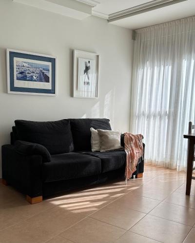 a black couch in a living room with a window at Apartamento Camino a Lancha in Miengo